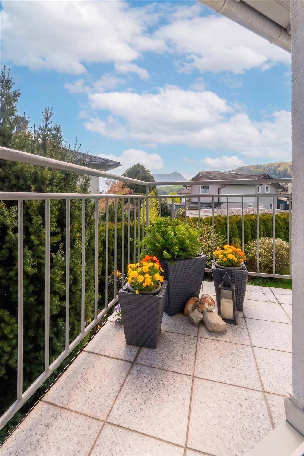 Gefliester Balkon mit Metallgeländer, Topfpflanzen und Blick auf die Umgebung.
