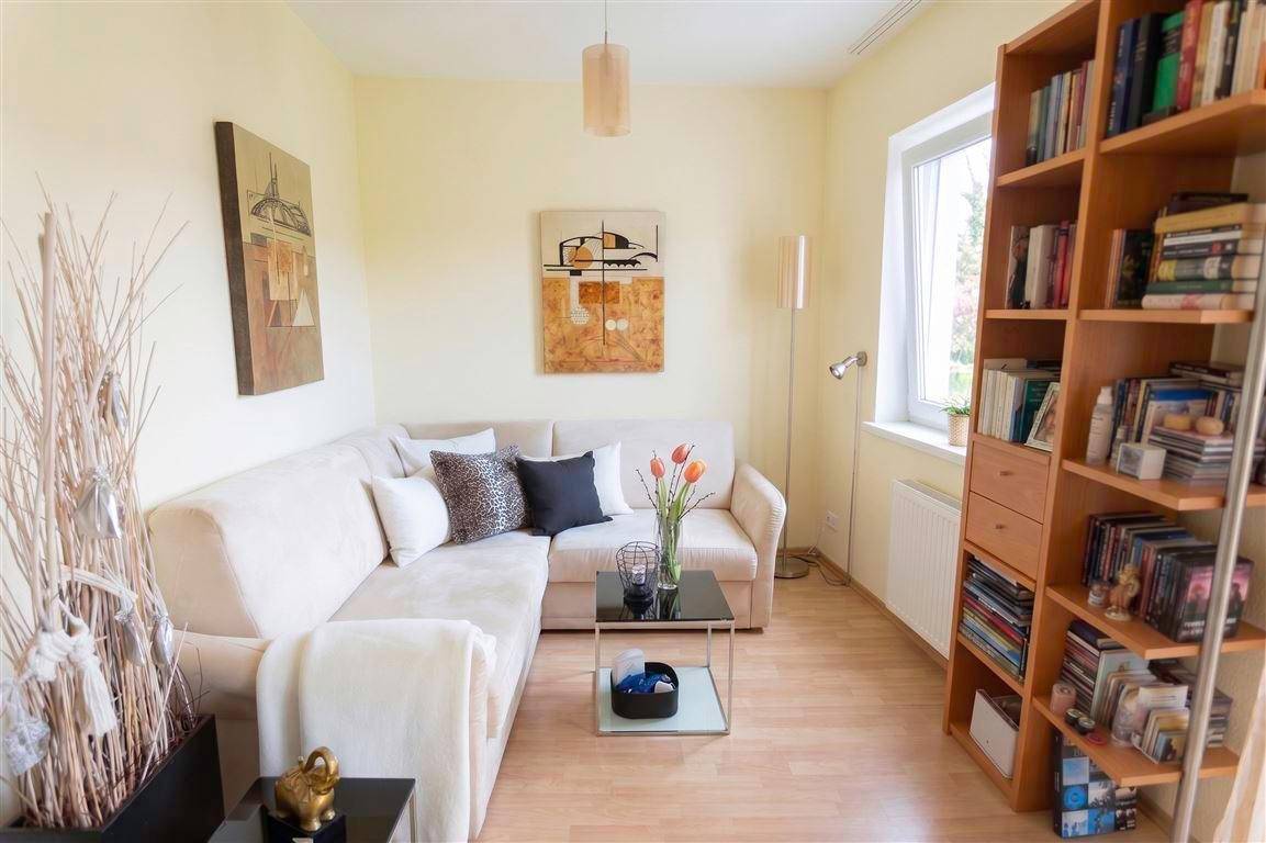 Gemütlicher Wohnbereich mit Ecksofa, Bücherregal und hellem Laminatboden.