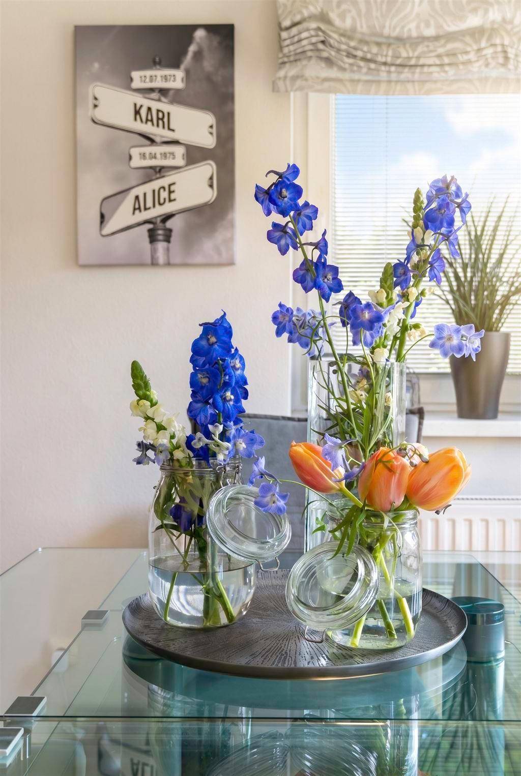 Nahaufnahme von frischen Blumen in Vasen auf einem Glastisch als Dekorationselement.