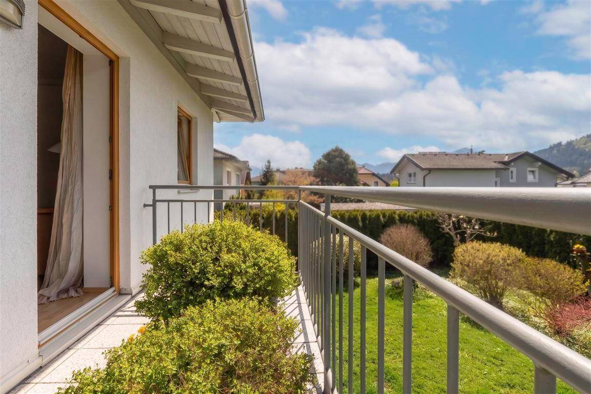 Der Balkon bietet einen seitlichen Blick auf die Nachbarschaft und die grüne Umgebung unter blauem Himmel.
