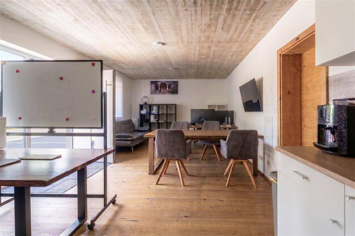 Geräumiger offener Wohnbereich mit Holzboden, Betondecke und mehreren Arbeitsplätzen.