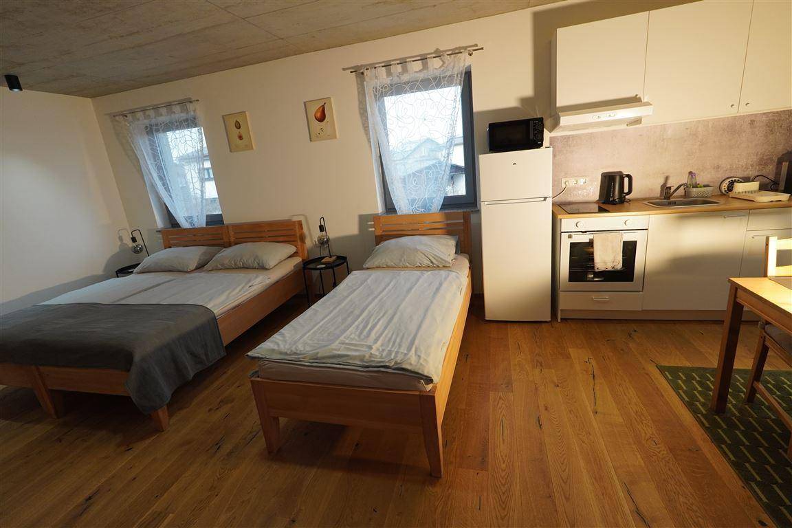 Studio-Apartment mit Schlafbereich, kleiner Küchenzeile und Essplatz am Fenster.