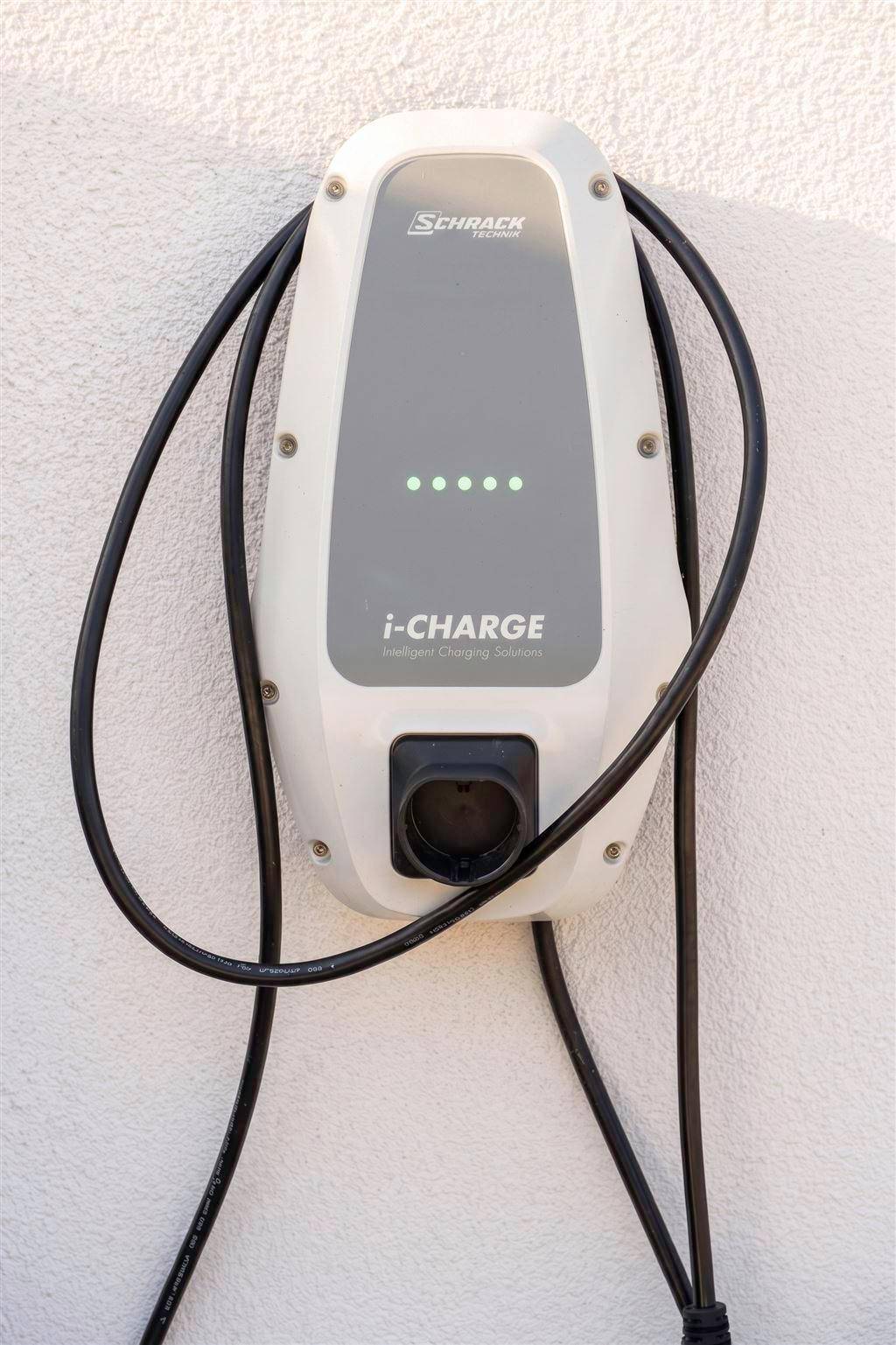 Nahaufnahme einer modernen Ladestation für Elektrofahrzeuge an der Außenwand des Gebäudes.