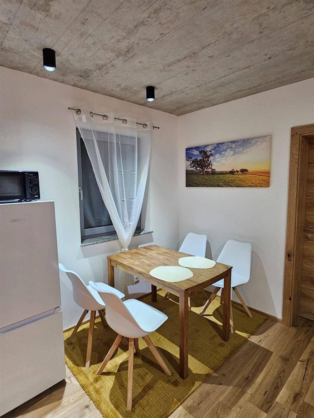 Gemütlicher Essbereich mit Holztisch, modernen Stühlen und freiliegender Betondecke.