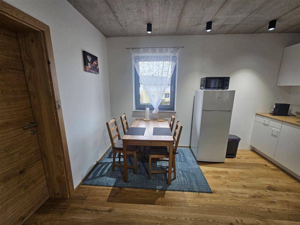 Essbereich mit Holztisch und Stühlen, angrenzend an eine kleine Küchenzeile.