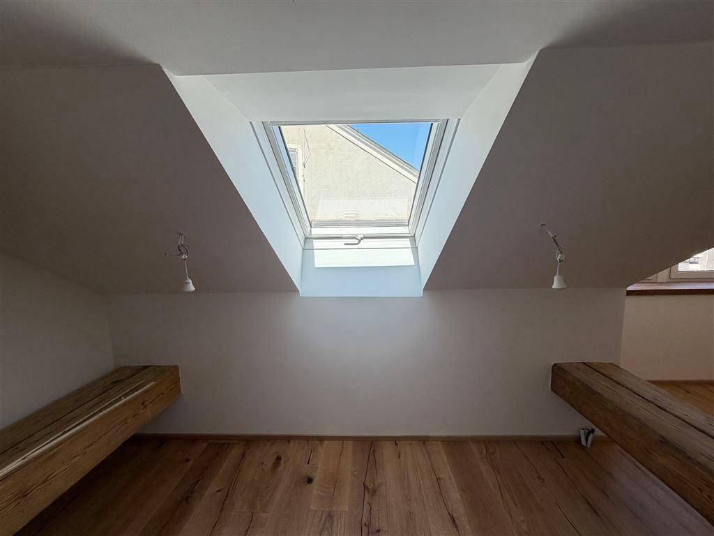 Dachbodenraum mit einem großen Dachfenster, das den Raum mit natürlichem Licht durchflutet, und Holzboden.