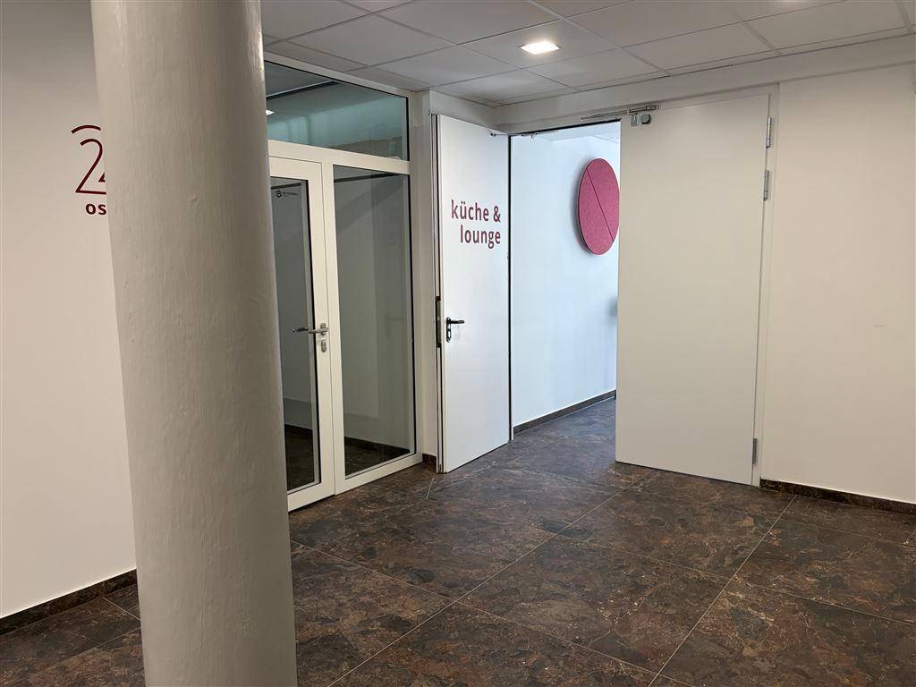 Heller Flur mit Fliesenboden, weißen Wänden und Türen, die zu einer Küche und Lounge führen.