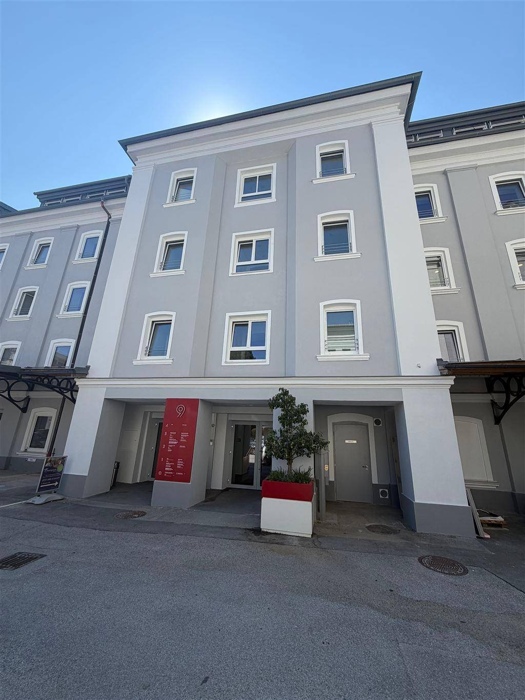 Eingangsbereich eines eleganten Wohngebäudes mit klassischer Fassade und klarem Himmel.