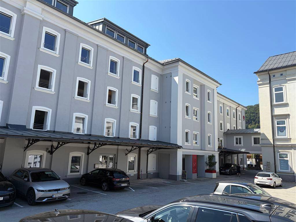 Außenansicht eines modernen Wohngebäudes mit Parkplätzen und klarem Himmel.
