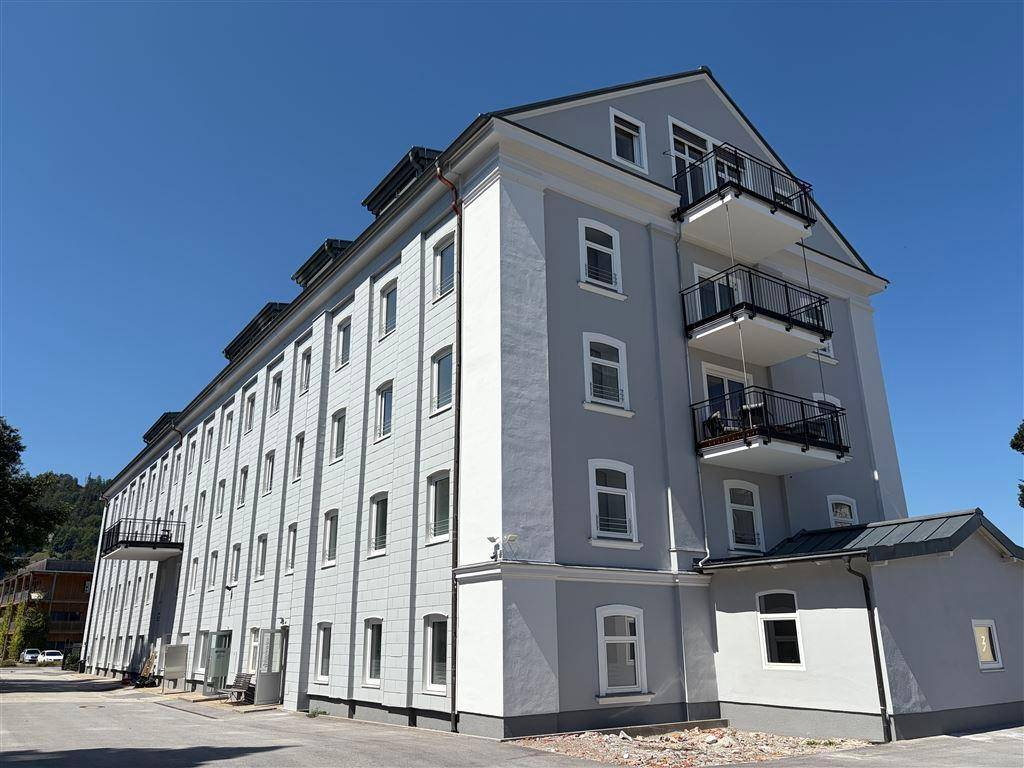 Seitenansicht eines modernen Wohngebäudes mit mehreren Balkonen und blauer Himmel.