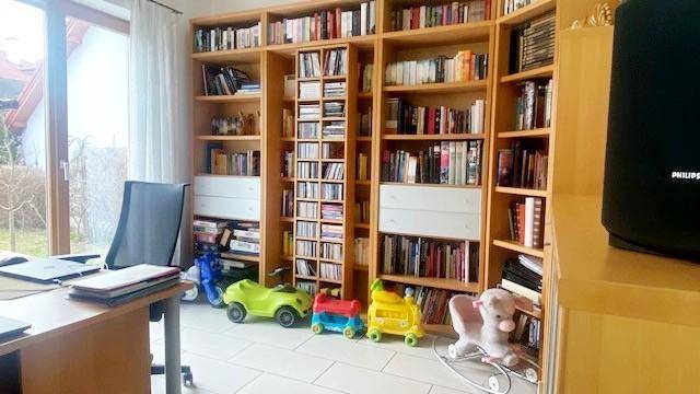 Arbeitszimmer mit Bücherregalen, Schreibtisch und Zugang zum Garten.