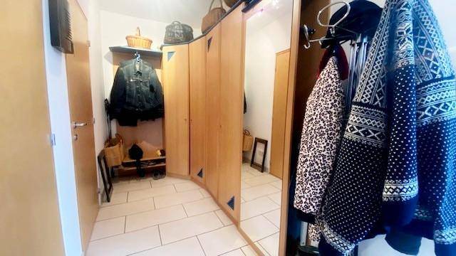Heller Eingangsbereich mit Garderobe, großem Spiegel und Fliesenboden.