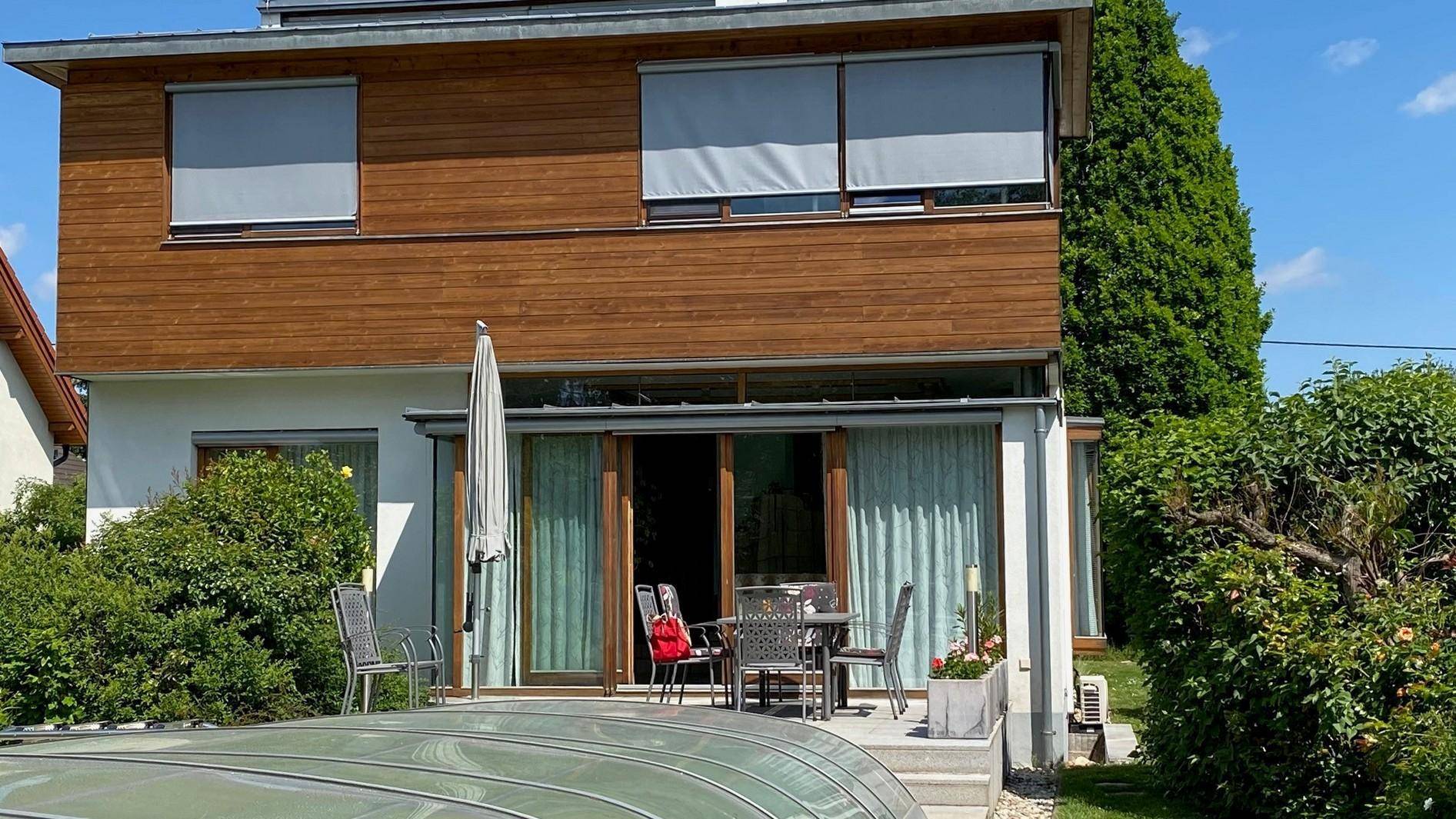Geräumige Terrasse mit Gartenmöbeln und Blick auf den überdachten Pool im Garten.