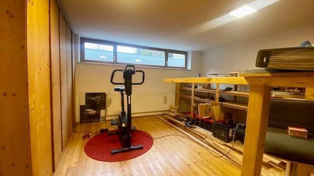 Fitnessraum im Keller mit Trainingsgerät und Holzvertäfelung.