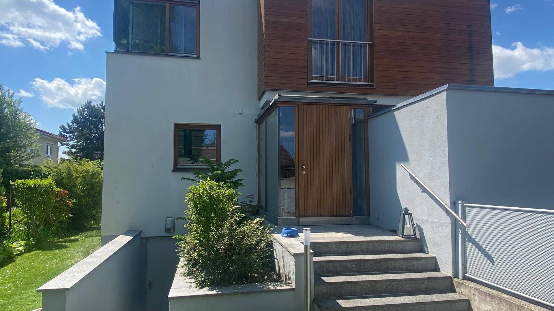 Haupteingang des modernen Hauses mit Holzverkleidung, Treppe und Geländer.