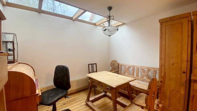 Esszimmer mit Holztisch, Bänken und Stühlen unter einem Oberlicht.