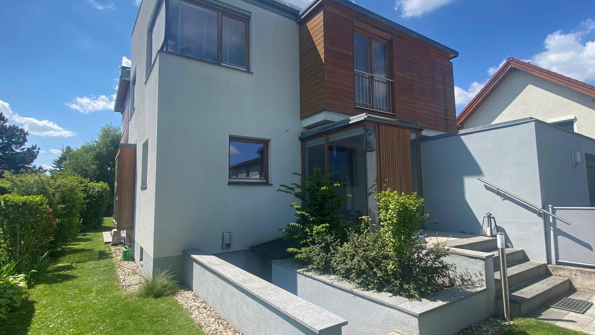 Eingangsbereich des modernen Hauses mit Holzverkleidung, Treppe und seitlichem Garten.