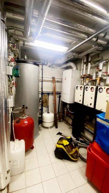 Heizungsraum im Keller mit Warmwasserspeicher und verschiedenen Installationen.