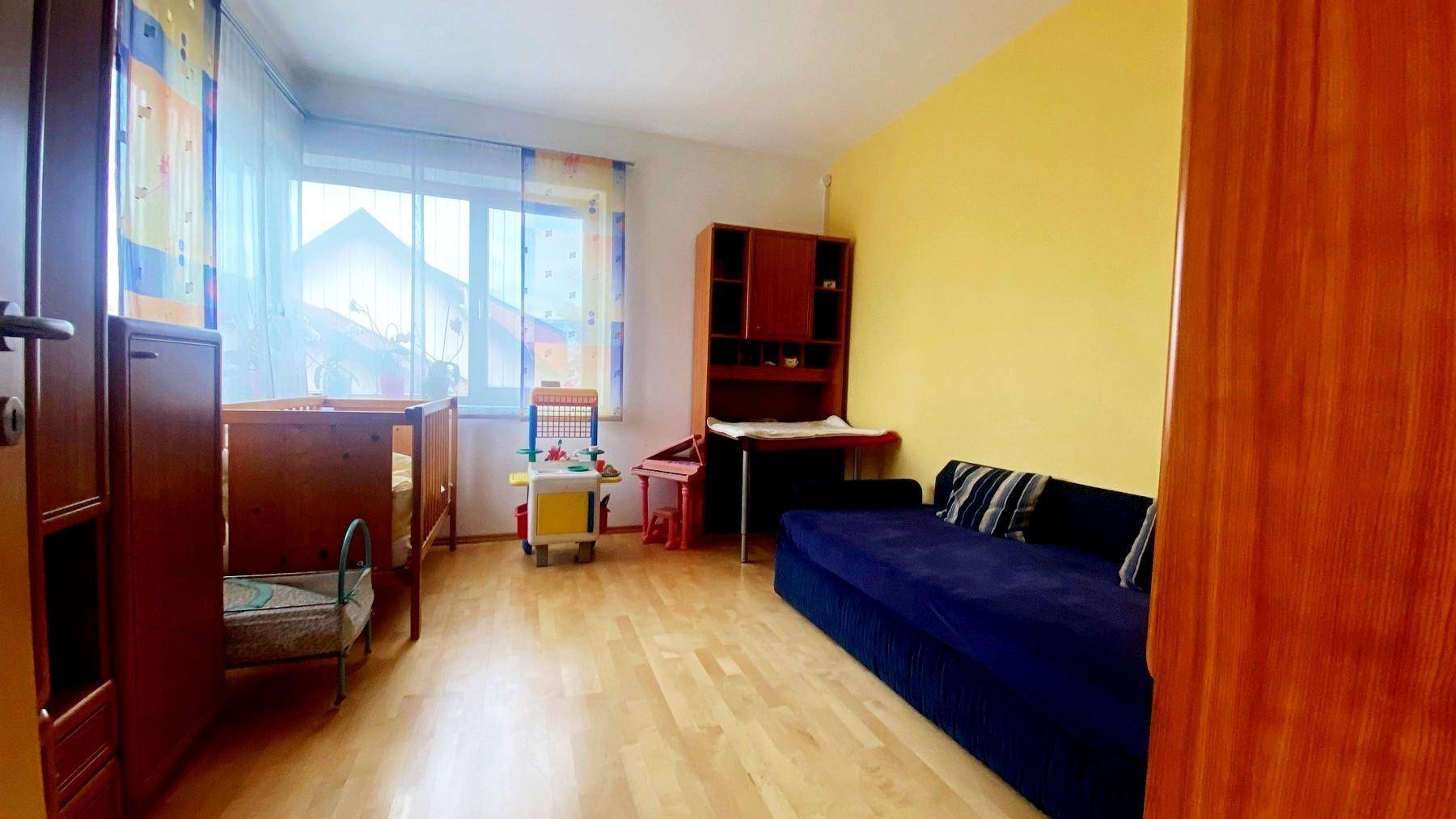Kinderzimmer mit gelben Wänden, Babybett und Schlafsofa.