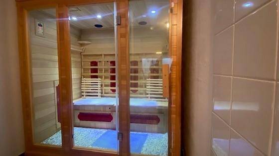 Moderne Sauna mit Holzbänken und Glasfront im Badezimmerbereich.