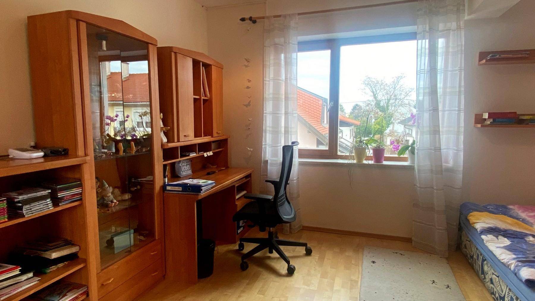 Schlafzimmer mit Schreibtisch, Holzmöbeln und Fenster mit Blick auf die Umgebung.