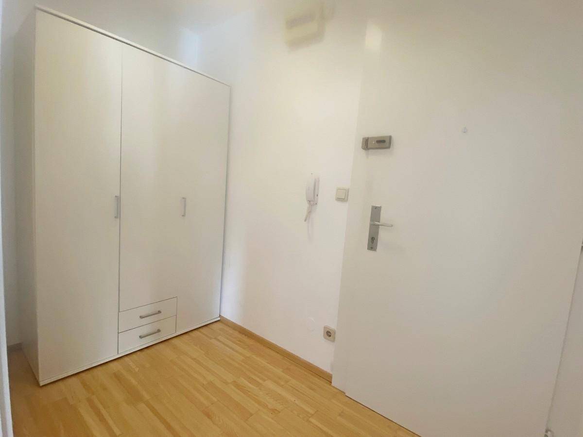 Kleiner Raum mit hellem Parkettboden und einem weißen Einbauschrank.