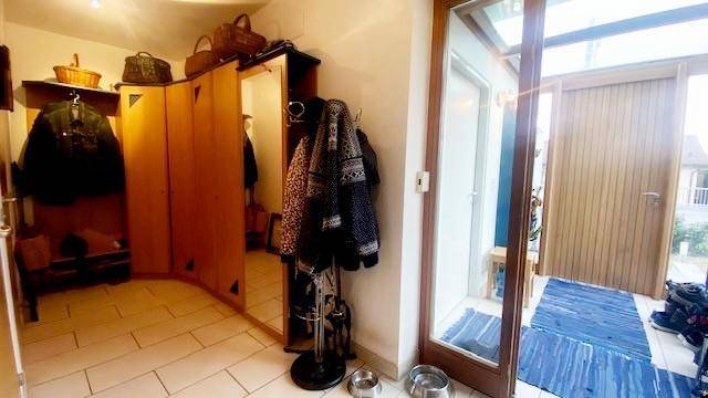 Eingangsbereich mit Garderobe, Spiegel und Zugang zu einem Wintergarten.