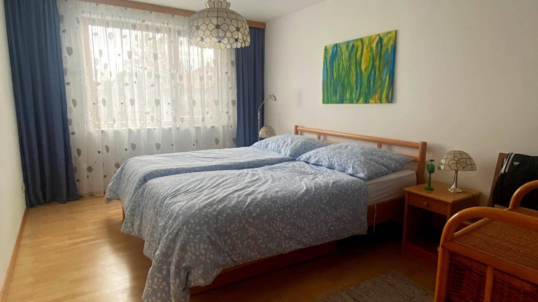 Helles Schlafzimmer mit zwei Einzelbetten, Holzboden und großem Fenster.