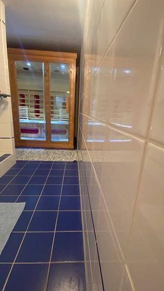 Badezimmer mit integrierter Sauna und blauen Bodenfliesen.