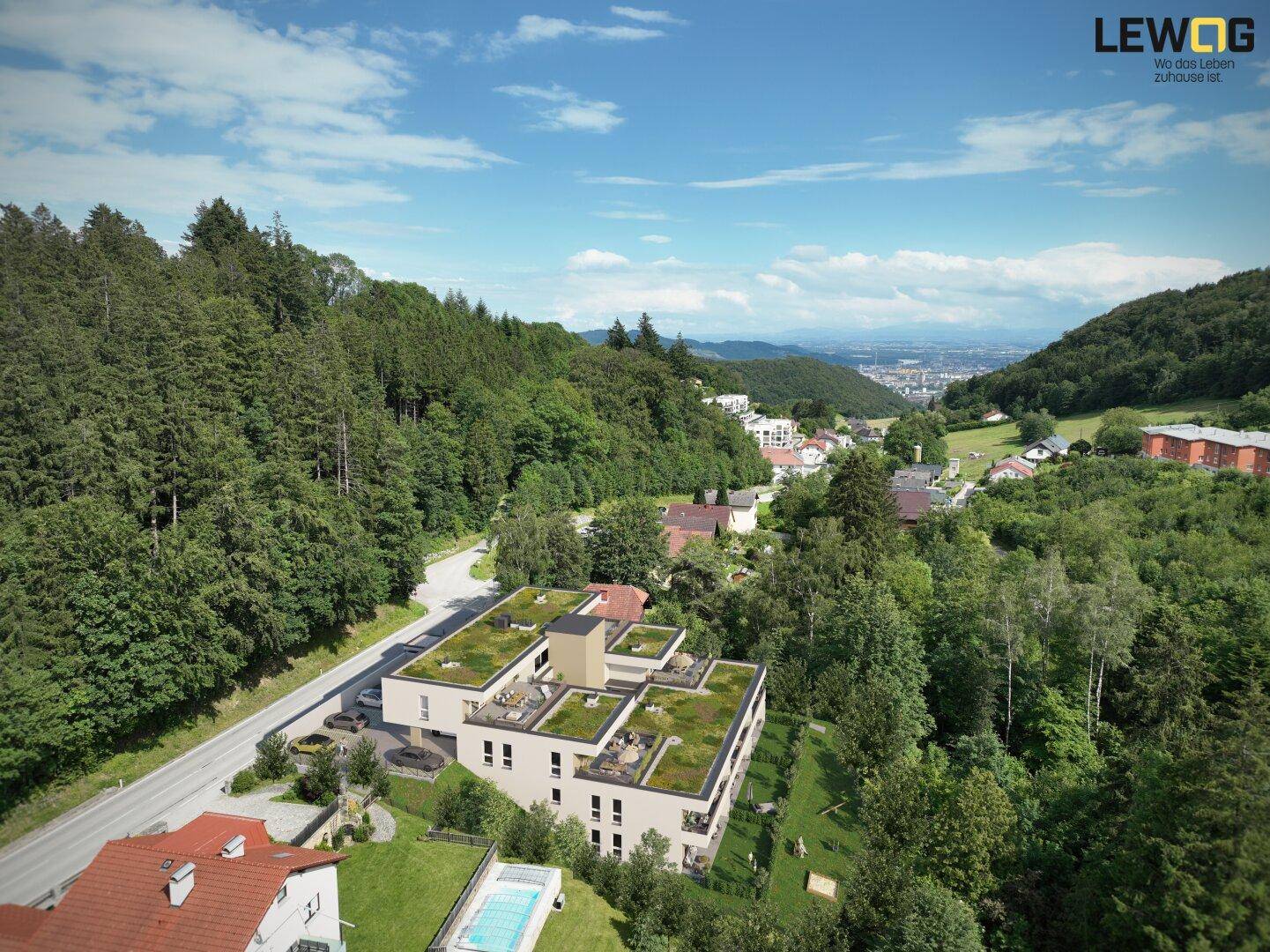 Luftaufnahme der modernen Wohnanlage eingebettet in die grüne Hügellandschaft mit Fernblick.