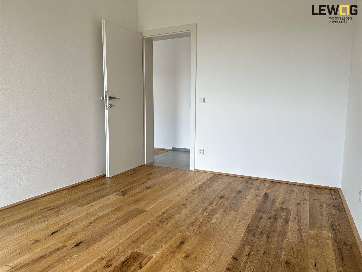 Helles Schlafzimmer mit Eichenparkett und weiß gestrichenen Wänden.
