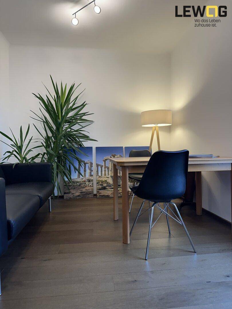 Heller Arbeitsbereich mit Holzboden, Schreibtisch und bequemer Sitzgelegenheit.