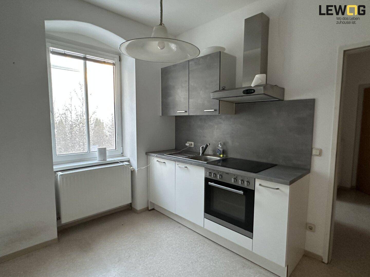 Moderne Küche mit weißen und grauen Schränken, Induktionskochfeld und Dunstabzugshaube.