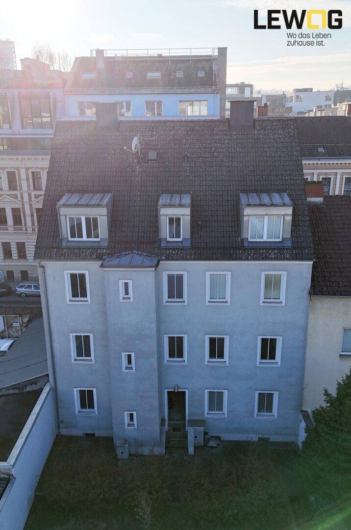 Ansicht des Mehrfamilienhauses von hinten mit Blick auf das Dach und die umliegenden Gebäude.
