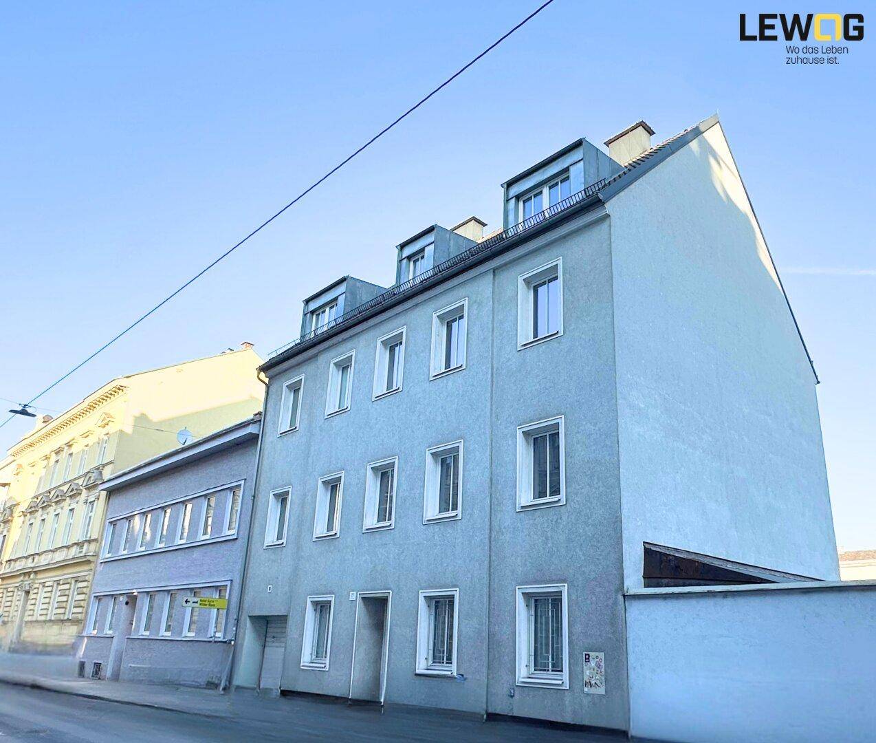 Seitenansicht des Wohngebäudes von der Straße aus mit mehreren Fenstern und Dachgauben.