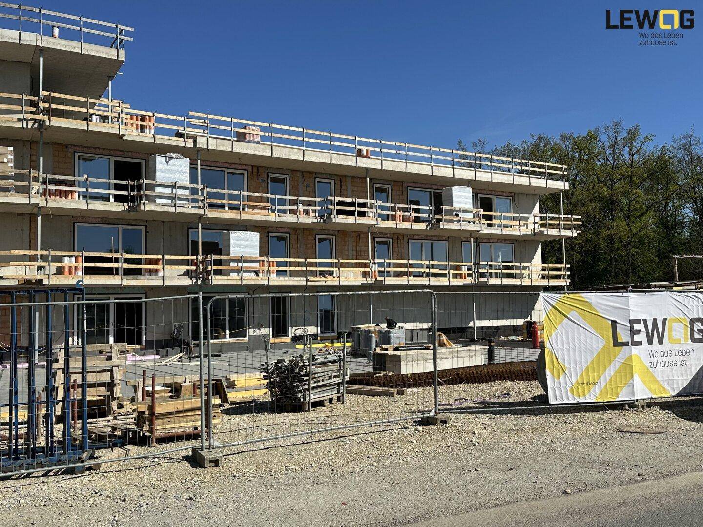 Neubau eines mehrstöckigen Gebäudes mit Gerüst und großen Fensterfronten auf der Baustelle.