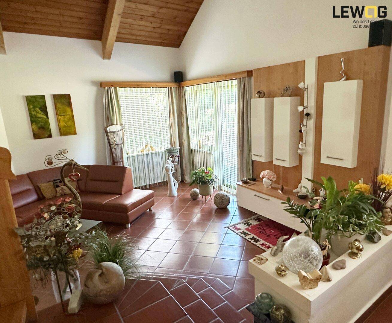 Gemütliches Wohnzimmer mit Terrakotta-Fliesenboden, Holzbalkendecke und großen Fenstern zum Garten.