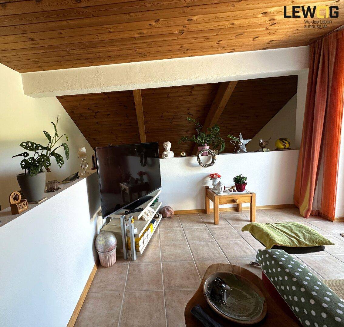 Gemütlicher Dachbodenraum mit Holzbalkendecke, Fliesenboden und Fernseher, ideal als Rückzugsort.