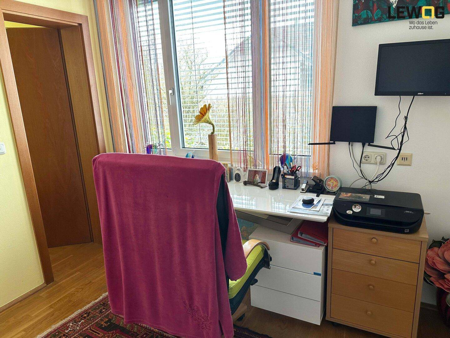 Funktionales Arbeitszimmer mit Schreibtisch am Fenster, Laminatboden und viel Tageslicht.