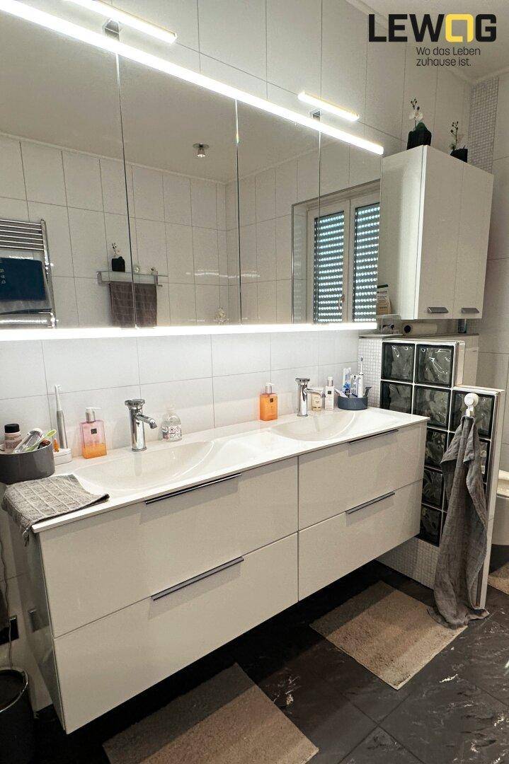 Modernes Badezimmer mit Doppelwaschbecken, großem Spiegelschrank und weißen Fliesen.