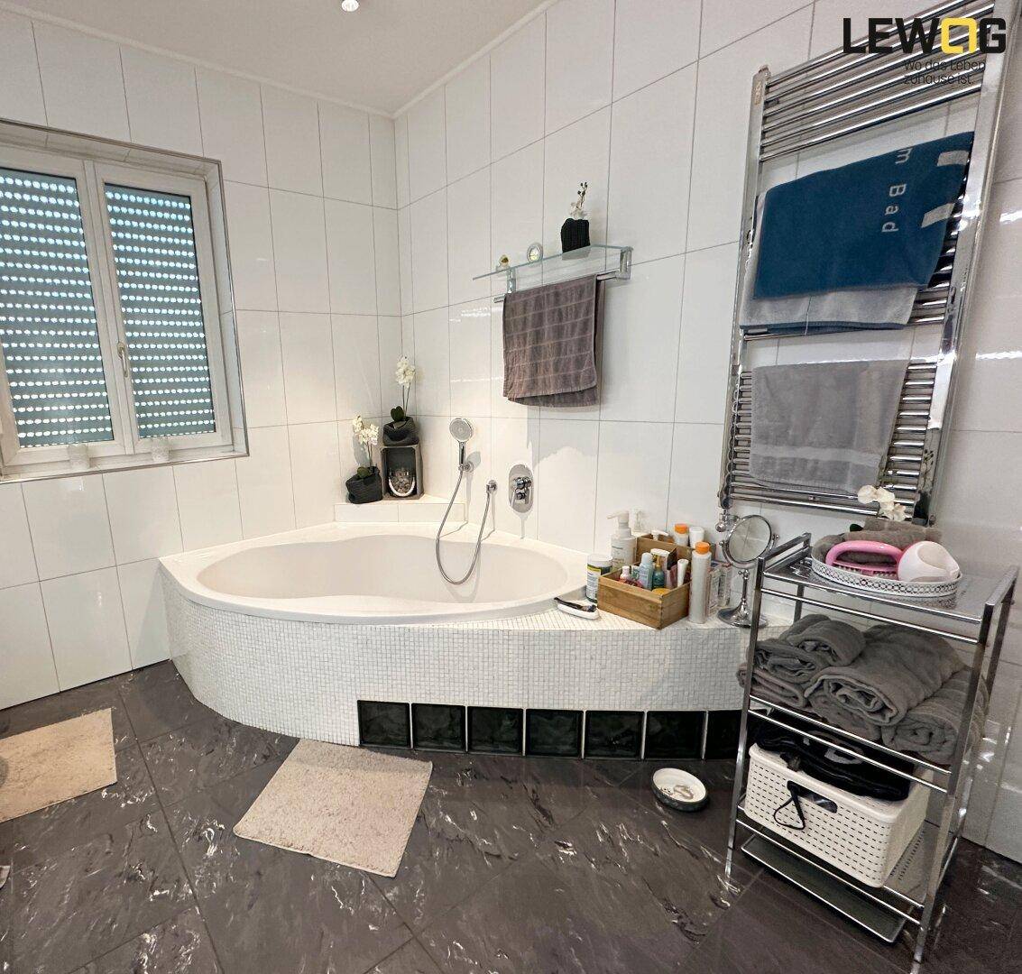 Geräumiges Badezimmer mit Eckbadewanne, Fenster und beheiztem Handtuchhalter.
