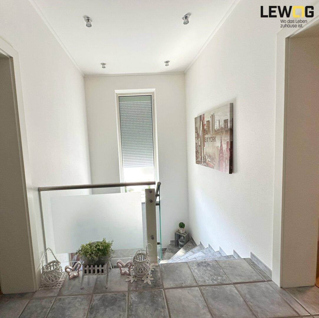 Heller Treppenaufgang mit modernem Glasgeländer und Fenster für natürliches Licht.