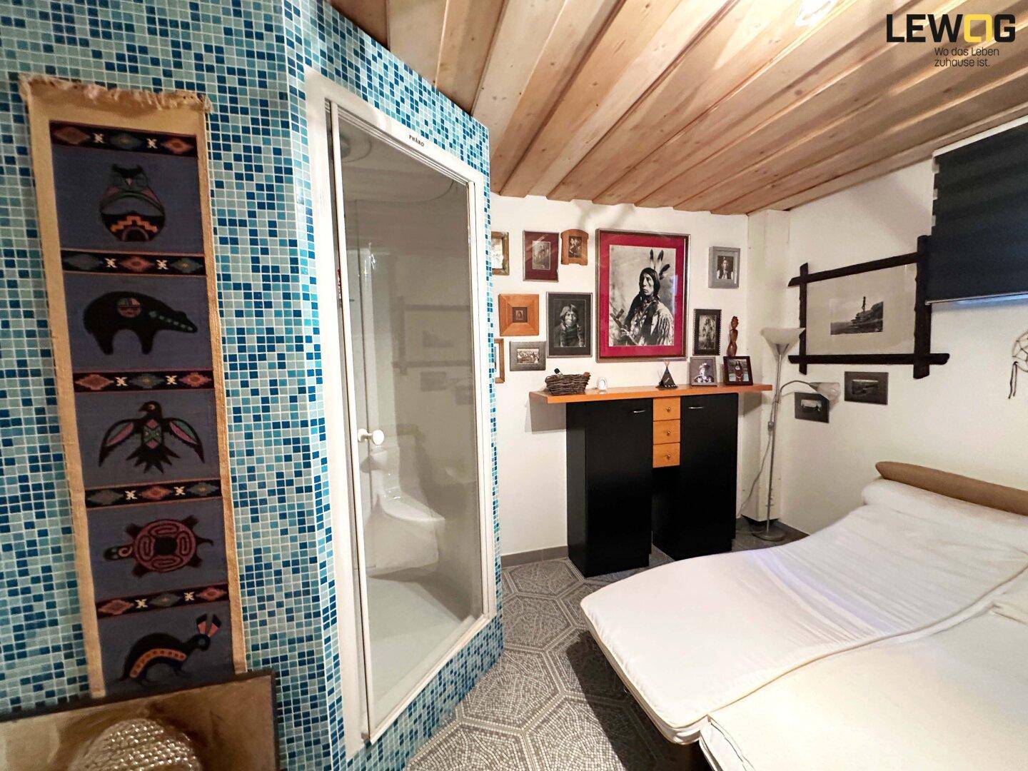 Gemütliches Schlafzimmer mit Holzbalkendecke, integrierter Dusche und farbigen Mosaikfliesen.