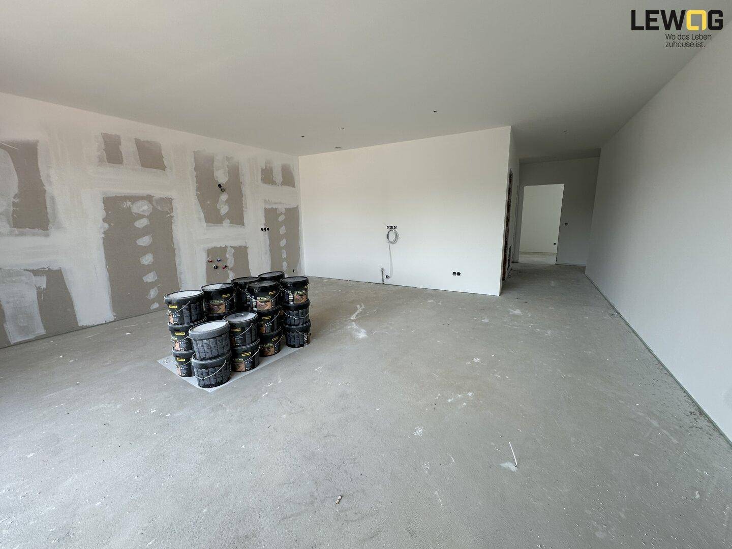 Großer, unfertiger Wohnbereich mit Betonboden und vorbereiteten Wänden für den Innenausbau.