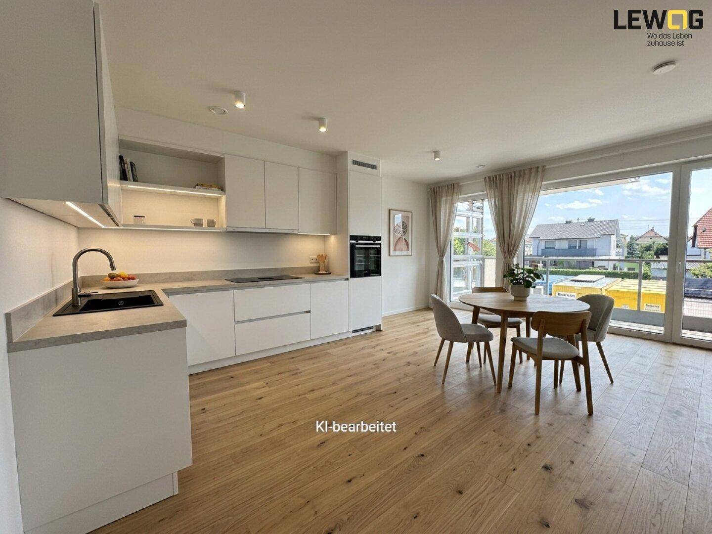Moderne, offene Wohnküche mit weißen Schränken, Holzboden und Zugang zum Balkon mit Weitblick.
