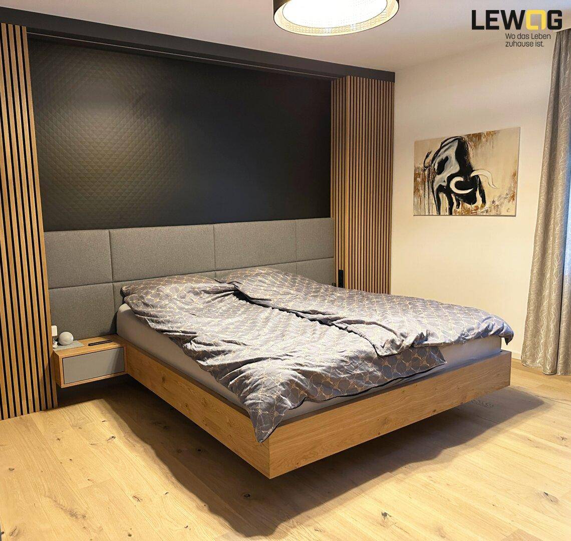 Modernes Schlafzimmer mit schwebendem Bett, dunkler Akzentwand und Holzvertäfelung.