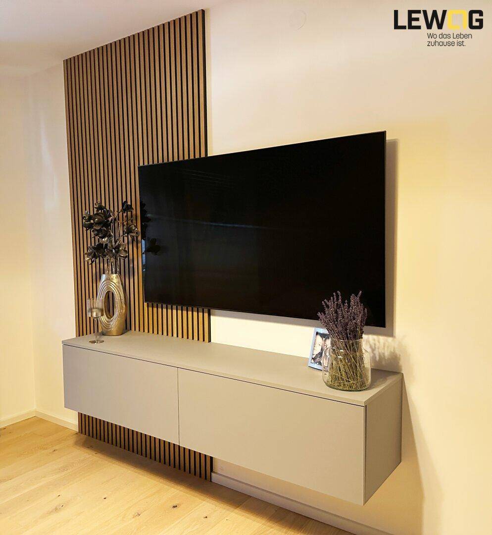 Schlafzimmer mit wandmontiertem Fernseher, schwebendem Sideboard und Holzlamellenwand.
