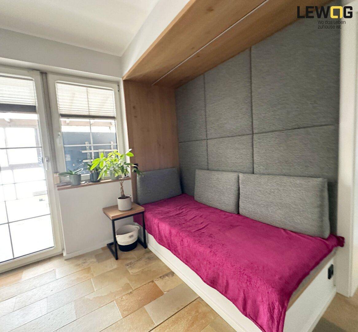 Gemütliches Zimmer mit Tagesbett, gepolsterter Wand und Terracotta-Fliesenboden.