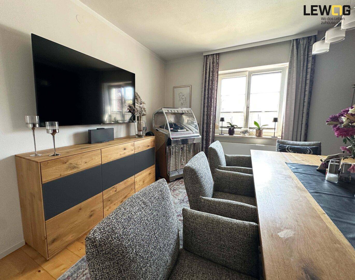 Essbereich mit langem Holztisch, bequemen Stühlen und einem Sideboard mit Fernseher.