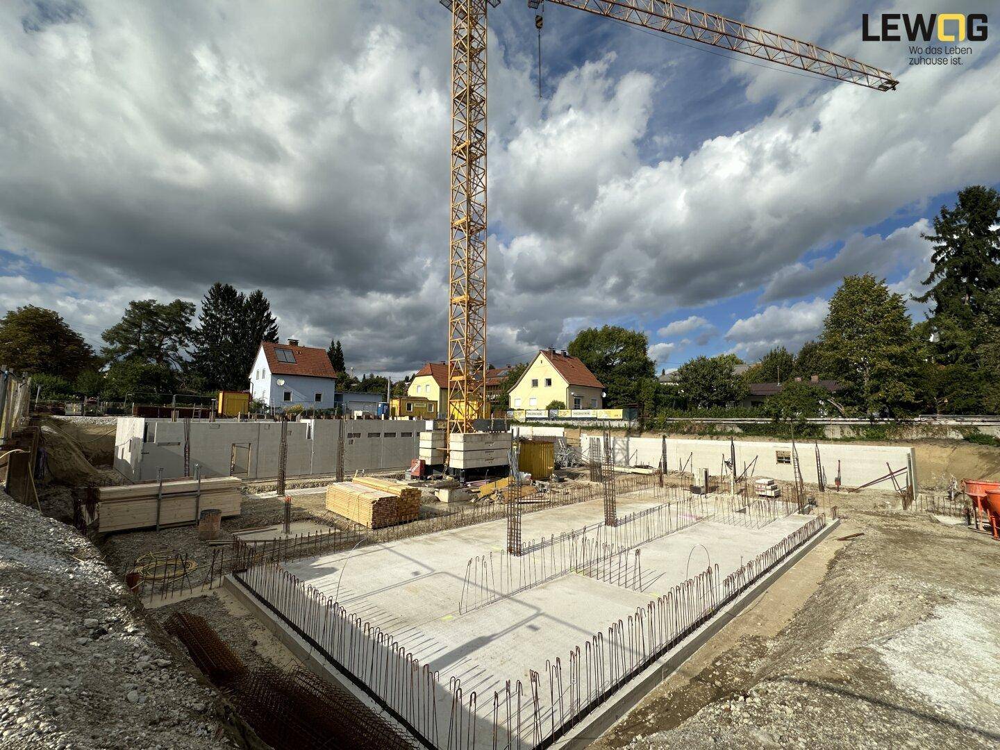 Baustelle mit Kran und Fundamentarbeiten für ein neues Gebäude in ländlicher Umgebung.